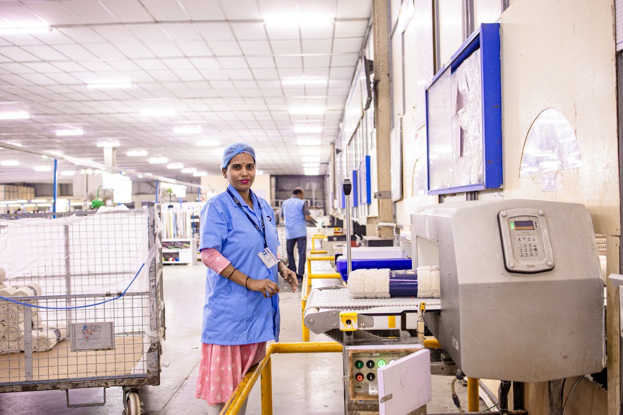 A female worker in blue uniform operating a textile machine in a factory.